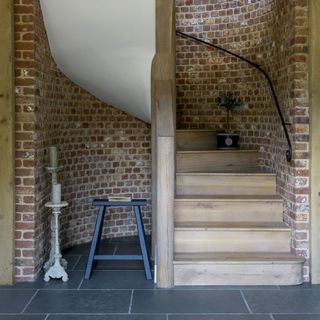 wooden staircase with bricked wall