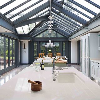 Glass extension inside kitchen with black ceiling beams