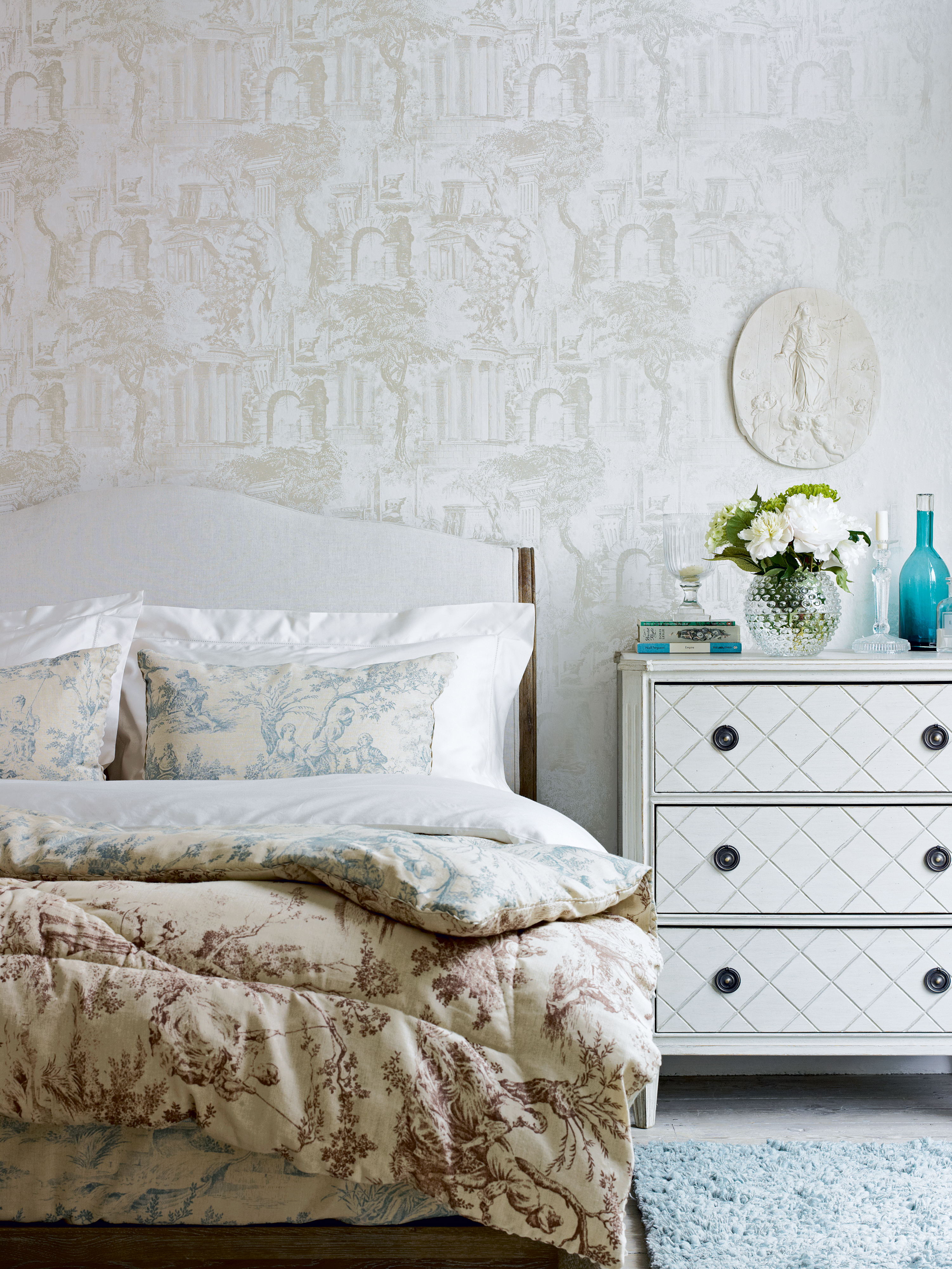 French-style bedroom with floral bed linen and antique style wallpaper