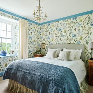 bedroom in Georgian farmhouse with floral wallpaper, blue painted coving and antique furniture