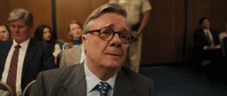 Nathan Lane as Dominick Dunne, sitting in the crowded gallery in a courtroom, in episode 208 of Monsters: The Lyle And Erik Menendez Story.