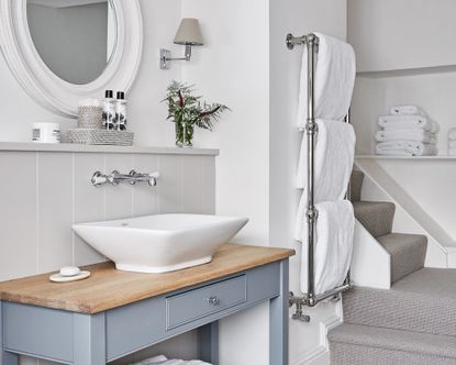 Bathroom with sink and vanity and mirror over, and towel rail with white towels