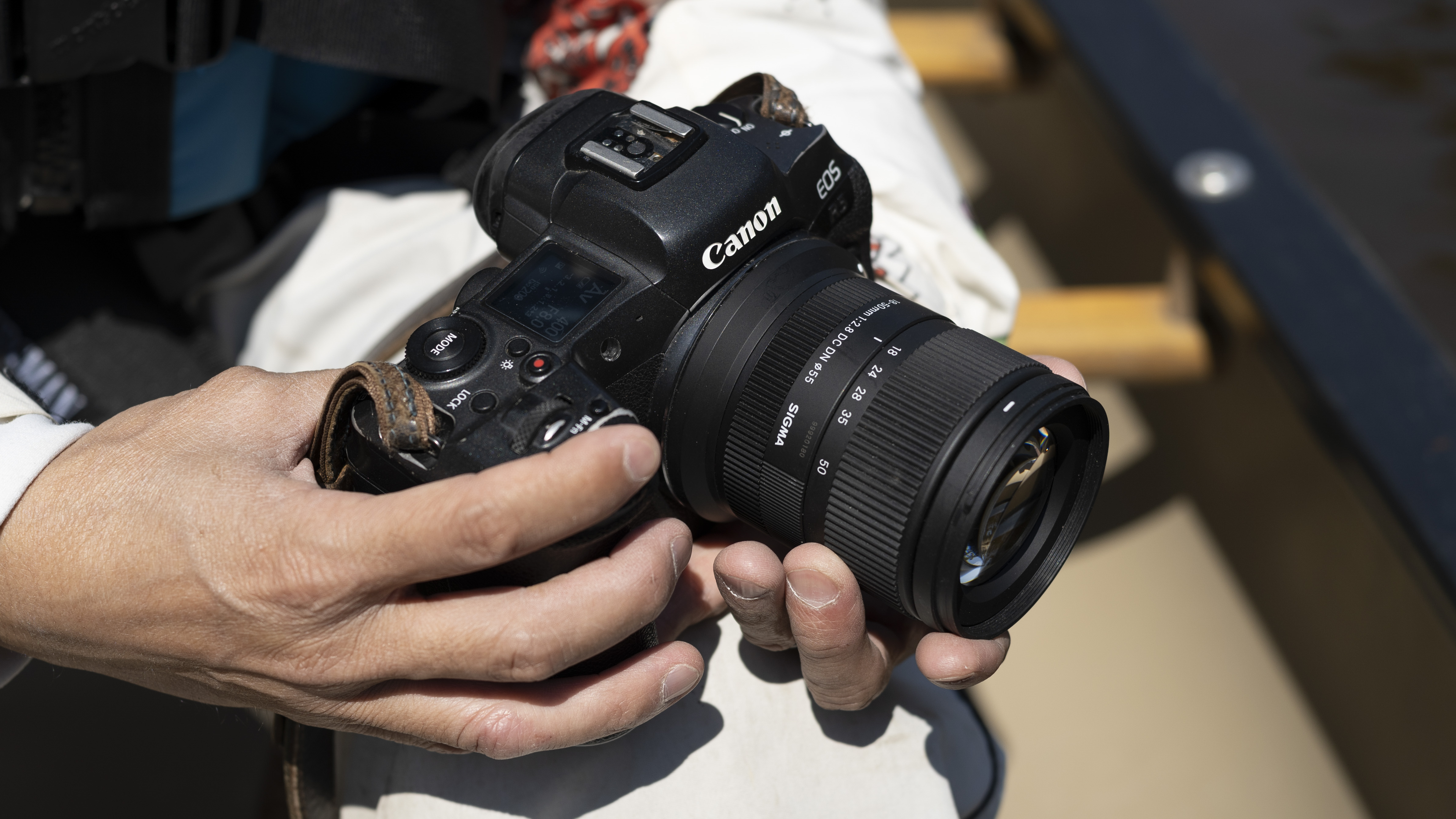 Sigma 18-50mm f/2.8 DC DN Contemporary lens in the hand, attached to a Canon EOS R5 camera