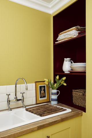 yellow laundry room with deep red painted shelving