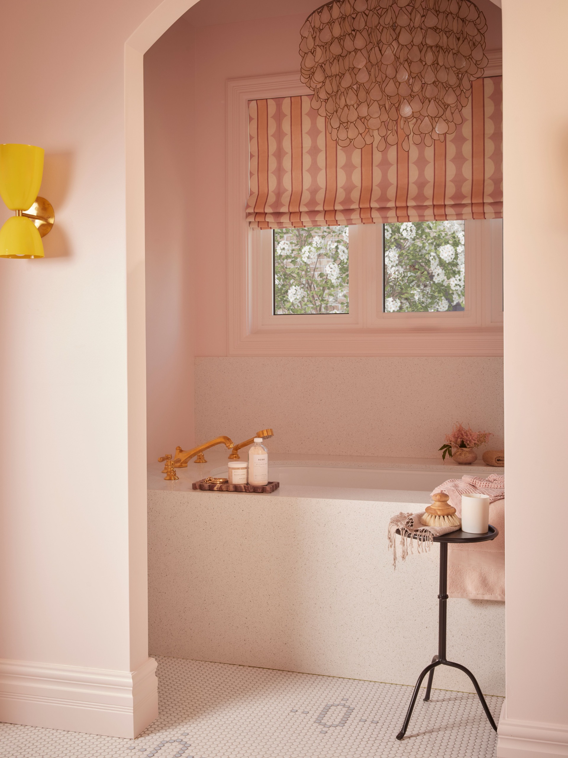 capiz shell chandelier over a built-in tub in a pink bathroom