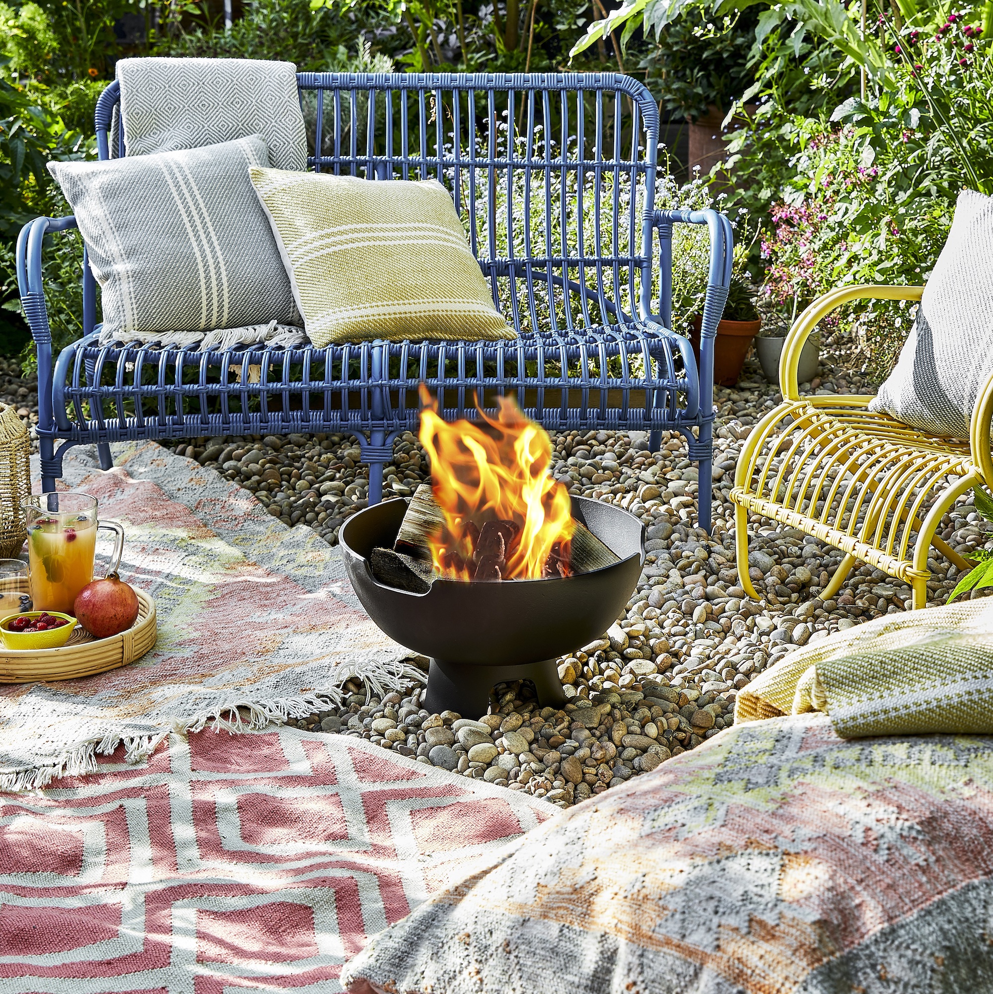 lit fire pit in garden with colourful chairs around