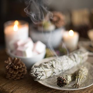 A plate with a burning sage next to lit candles