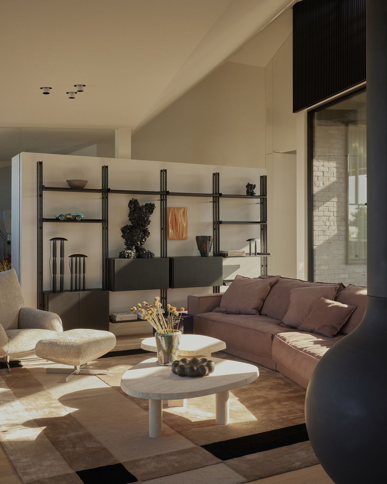 modern living room with room divider with shelving, nesting table, white armchair with ottoman, mauve sofa, and floating fireplace