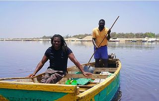 Africa with Ade Adepitan. Shows Ade on a boat in the Dead Sea