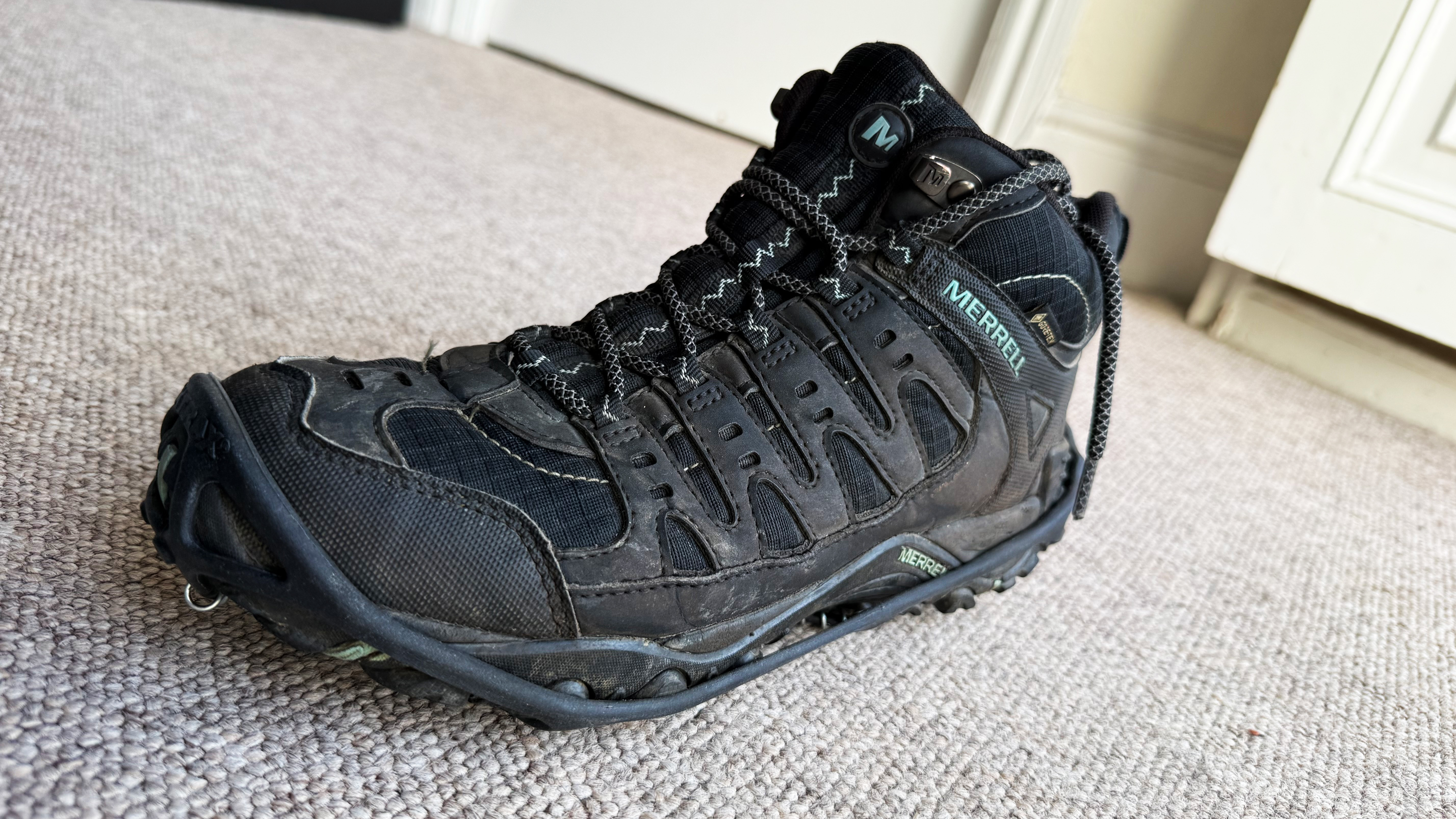 the merrell sport 3 hiking boots with yaktrax photographed inside, the sole, side, and top