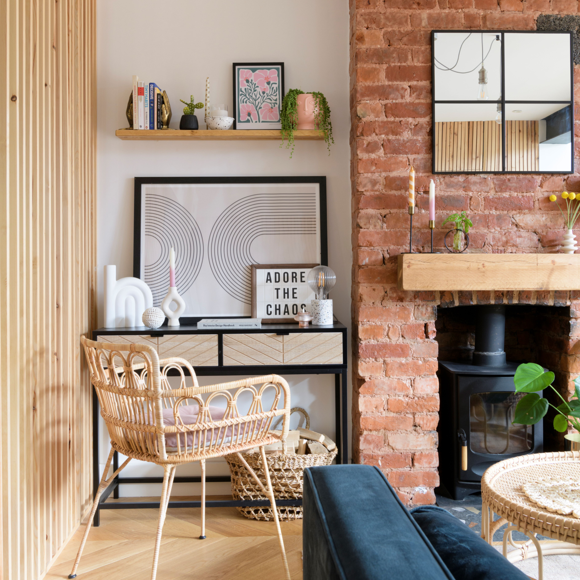 Living room with exposed brick feature wall and woodburner, open shelving, console table and chair