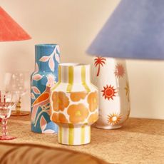 Colourful patterned vases from Oliver Bonas on neutral background, with purple and red lampshades. 
