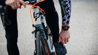 Person adjusting the fit of his cycling shoes while wearing the Polar Vantage V2