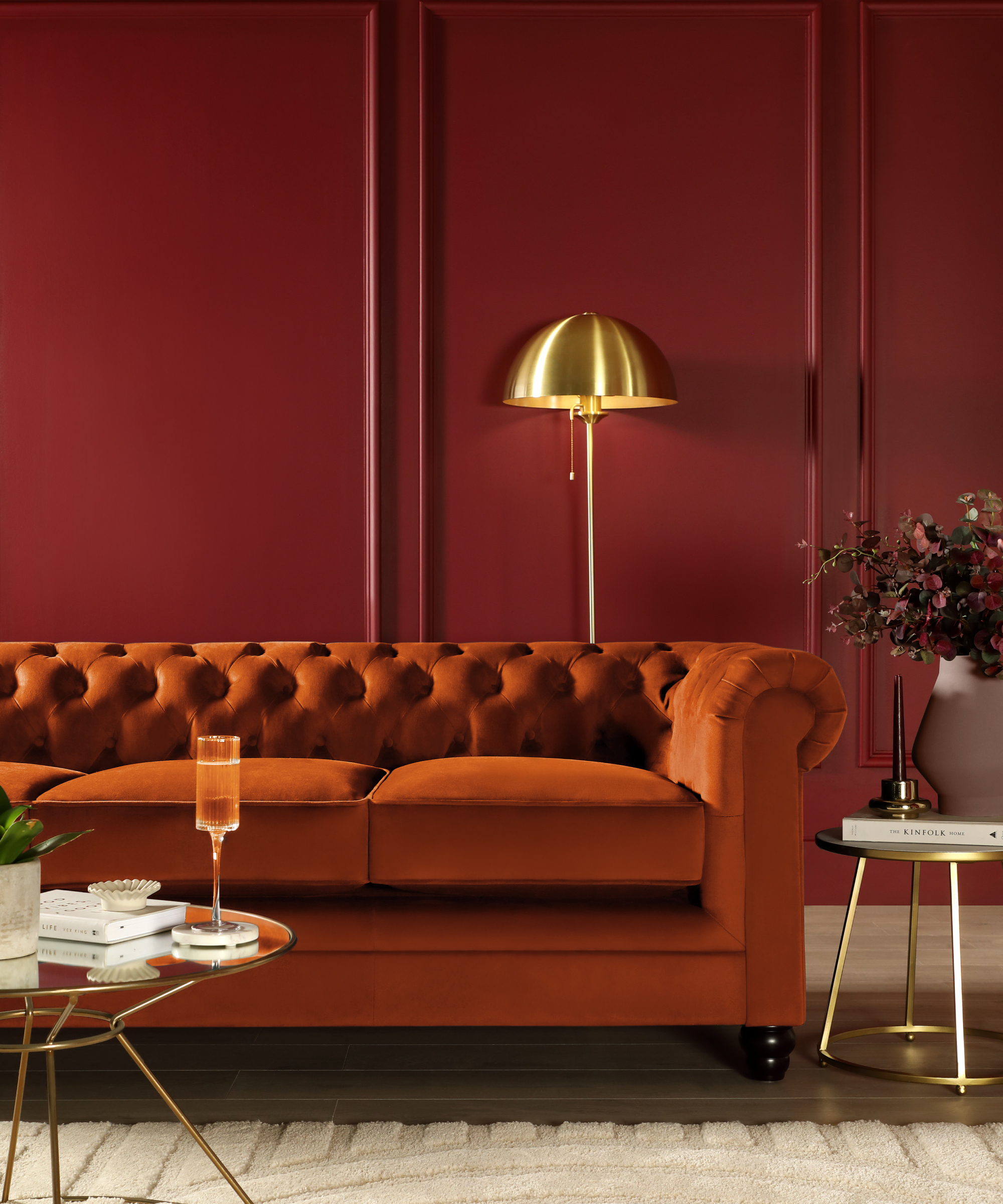 living room with burgundy panelled walls, burnt orange sofa and metallic finish furniture and lighting