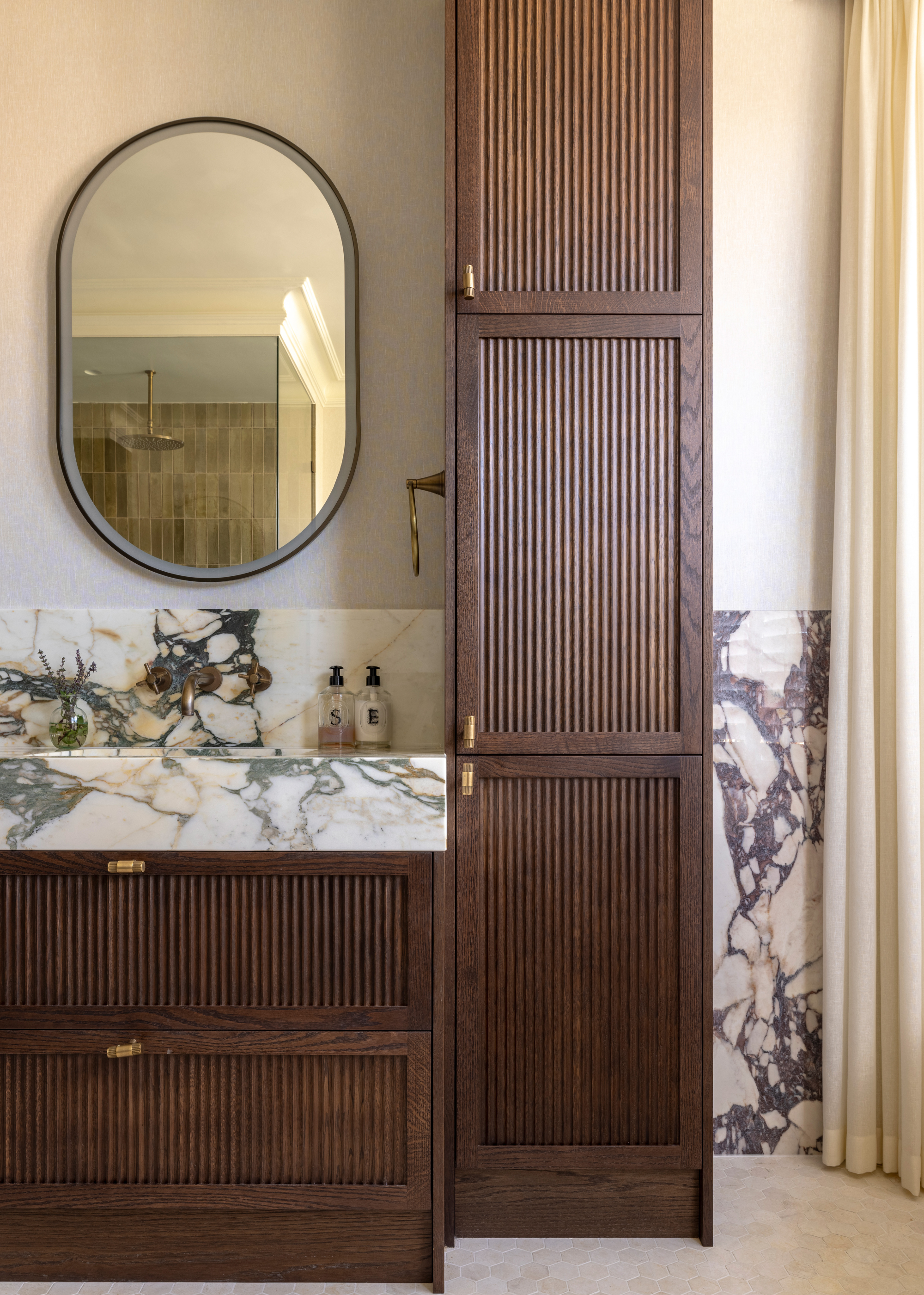 beautiful bathroom with slatted wooden cabinets and viola calcatta marble counters