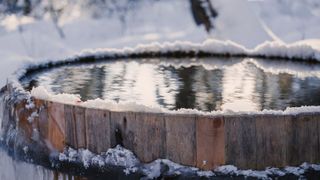 A cold plunge barrel covered with snow and ice
