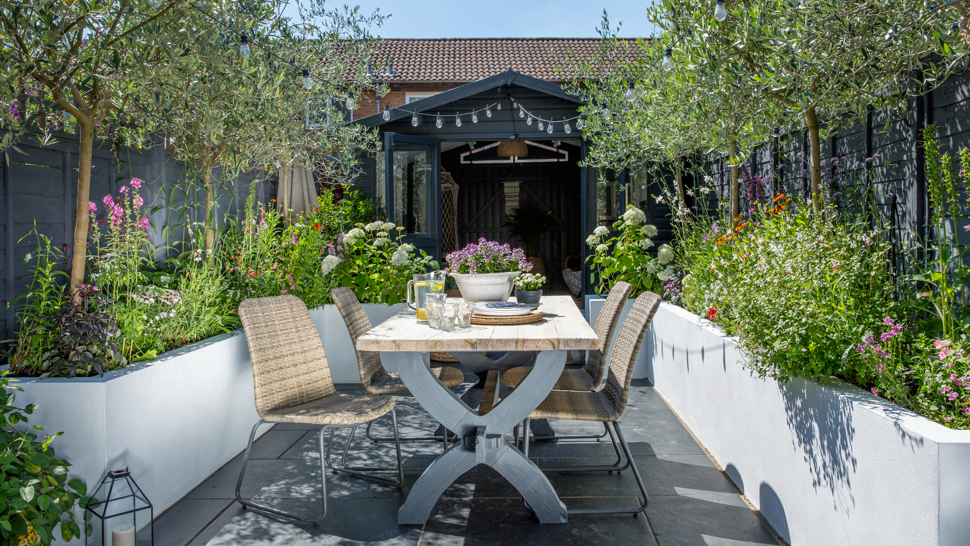 Small urban garden with outdoor dining table and chairs showing creative container planting in a small space