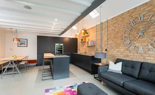 Contemporary open-plan kitchen, dining and living area with exposed brick wall