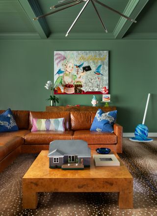 A small living room with dark green walls and a deep tan sectional sofa
