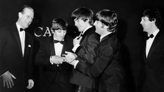 Prince Philip, Duke of Edinburgh, enjoys the joke as British pop group the Beatles fight over the single award that he has presented to them at the Carl-Alan Awards ceremony, held at the Empire Ballroom in Leicester Square