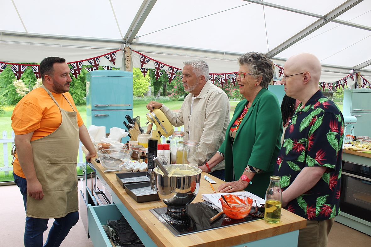 The Great British Bake Off judges talking to a baker
