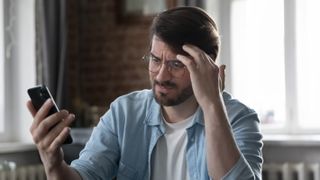 A man looking frustrated at his mobile phone