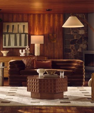 retro living room with warm wood paneling and velvet couch with green accents