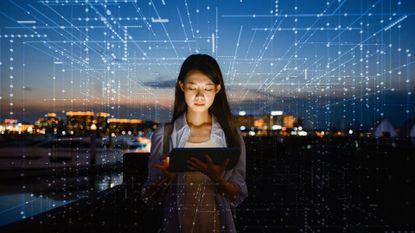 A photo of a woman in cybersecurity holding a tablet, surrounded by a dark cityscape lit with holographic data points.