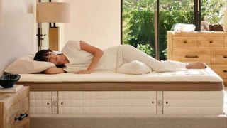 A woman with dark hair sleeps comfortably on her side on the Cloverlane Hybrid Mattress