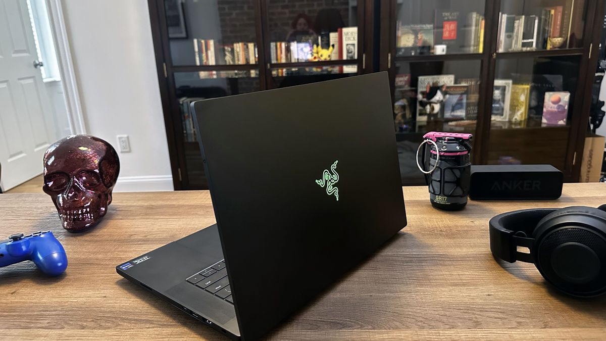 Razer Blade 16 laptop on a wooden table next to a wireless gaming headset and wireless controller