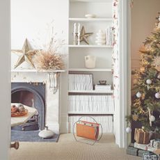 White painted living room with a grey fireplace on the left, built-in bookshelves on the wall, and a christmas tree on the right