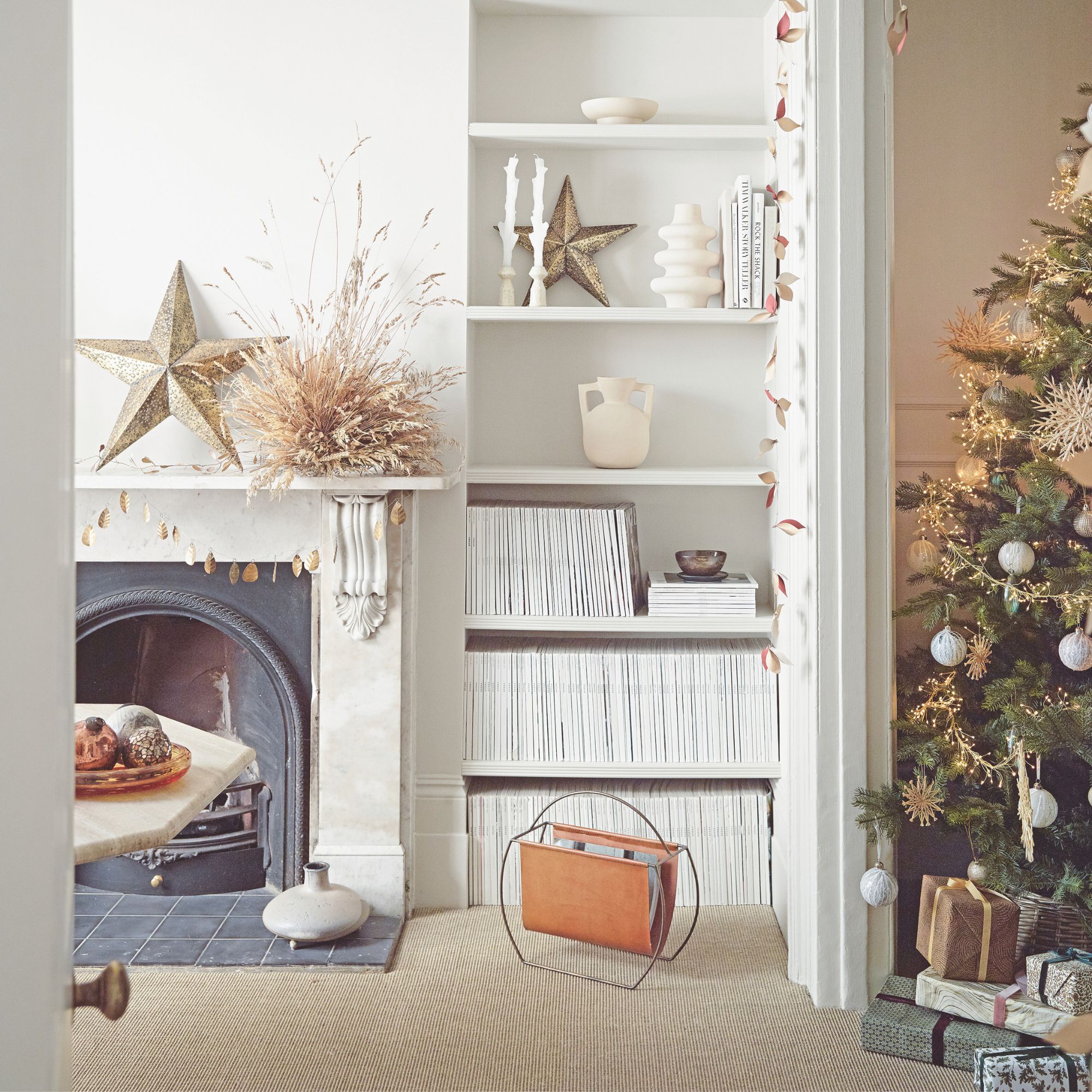 White painted living room with a grey fireplace on the left, built-in bookshelves on the wall, and a christmas tree on the right