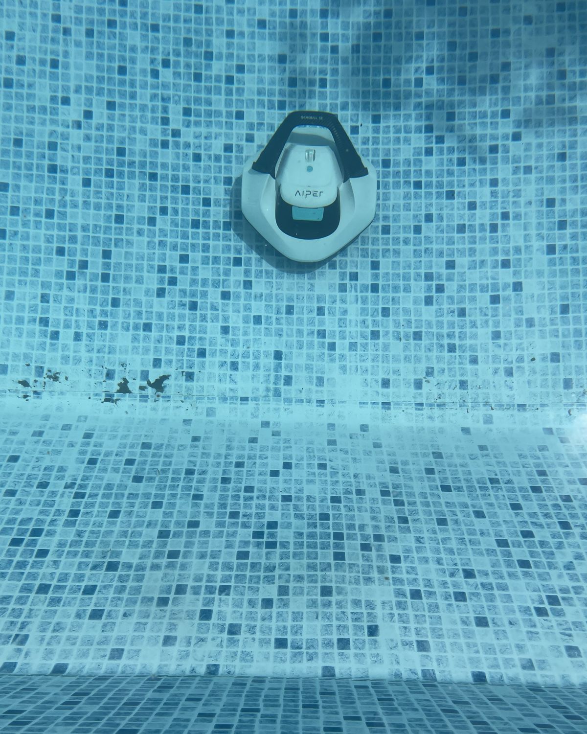 A robot vacuum on dirty pool floor