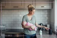 A woman touching a smart speaker while holding a newborn baby