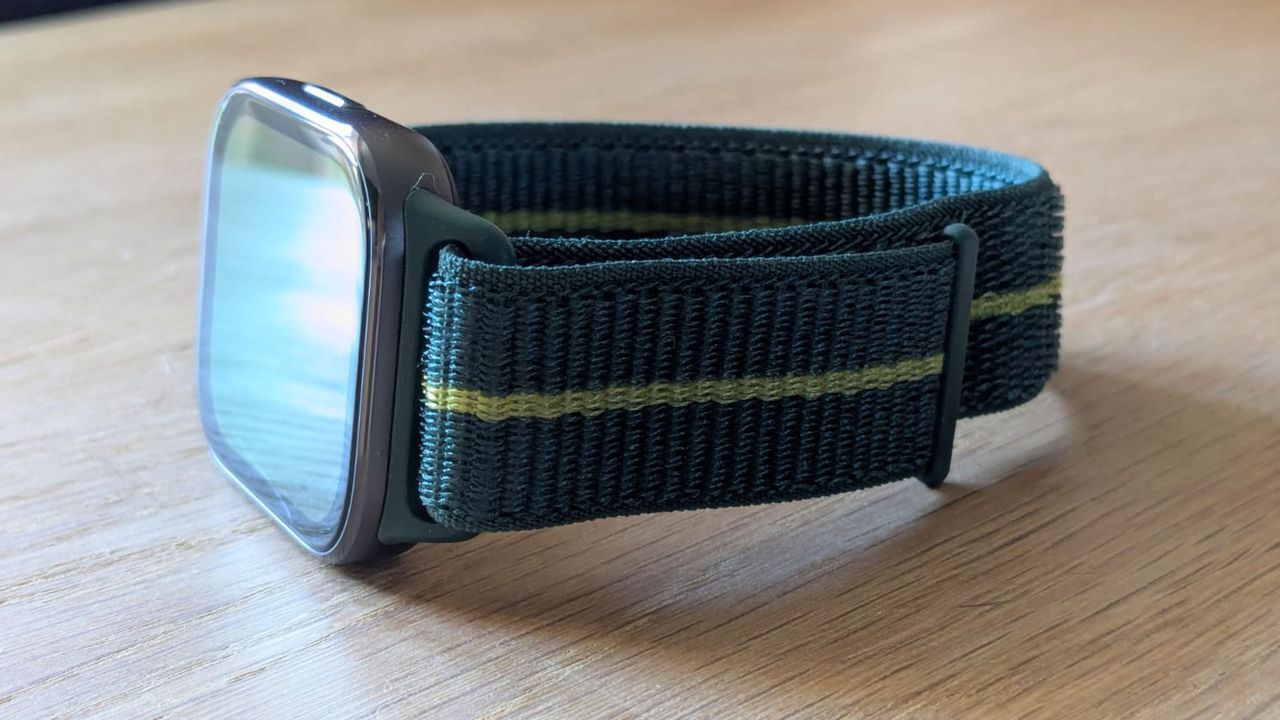 The Motorola Moto Fit Watch on a wooden table, showing the Velcro-adjustable strap.