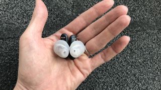 UE Fits earbuds in a hand on white background