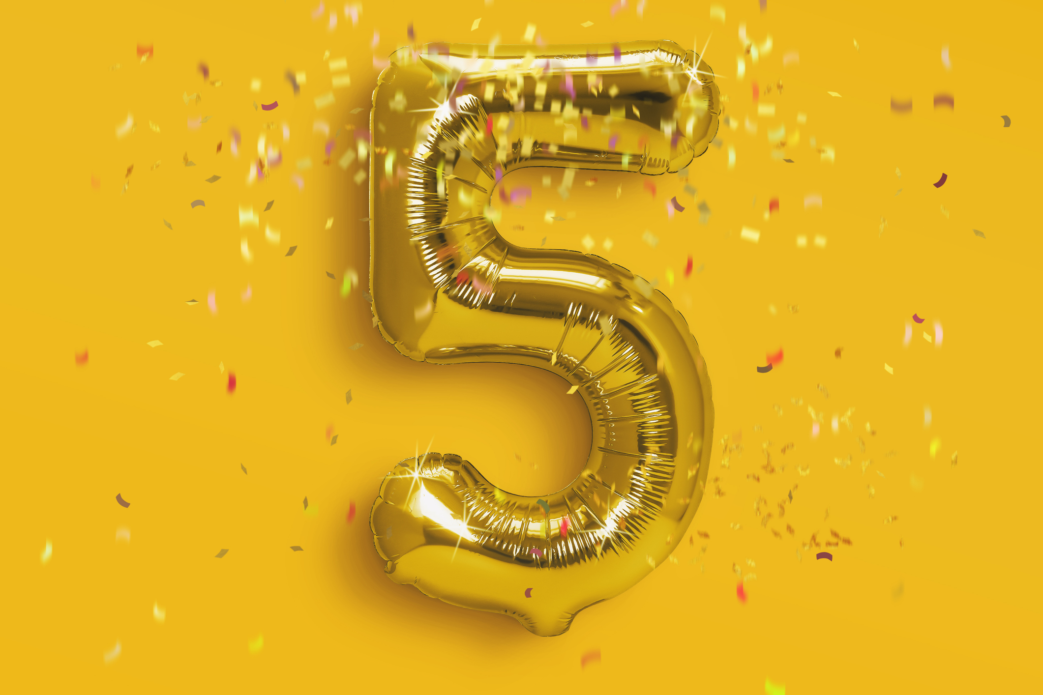 golden number 5 balloon with confetti on a yellow background