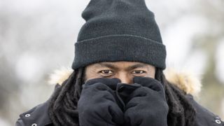 A portrait of a man in gloves and a hat bracing for the cold. 