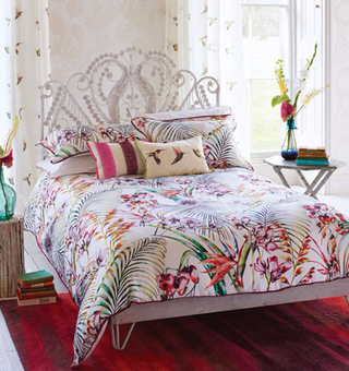 Harlequin Paradise Bed Linen on a white bed with a red carpet and white bedstead