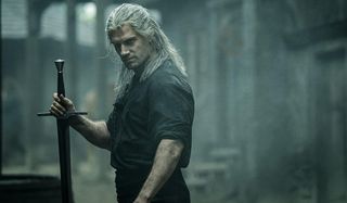 The Witcher Henry Cavill scowls while holding a sword upright