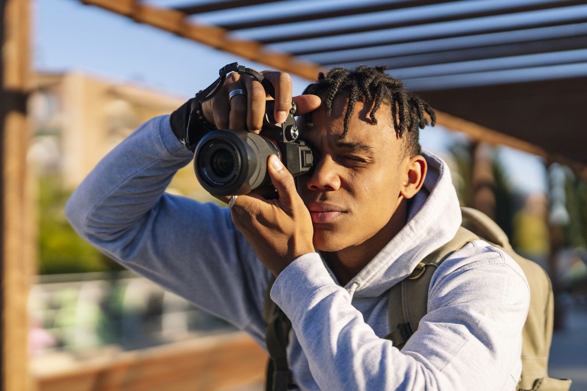 A young man takes a portrait photo with a DSLR.