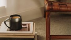Black coffee mug on a stack of magazines on awooden side table