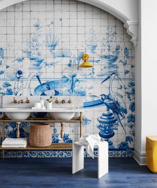 A blue themed bathroom with blue and white painted tiles featuring birds and water fountains