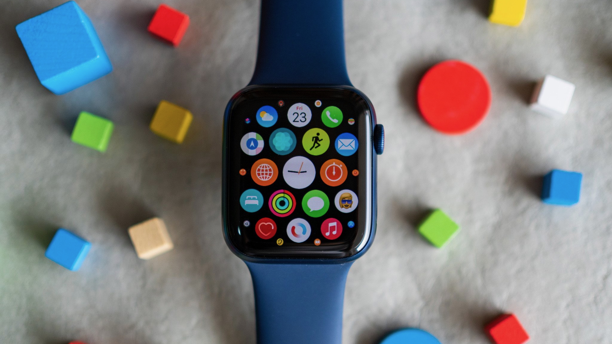 The Apple Watch Series 6 sitting above a felt floor with colorful blocks surrounding it, the display showing a collection of app icons.