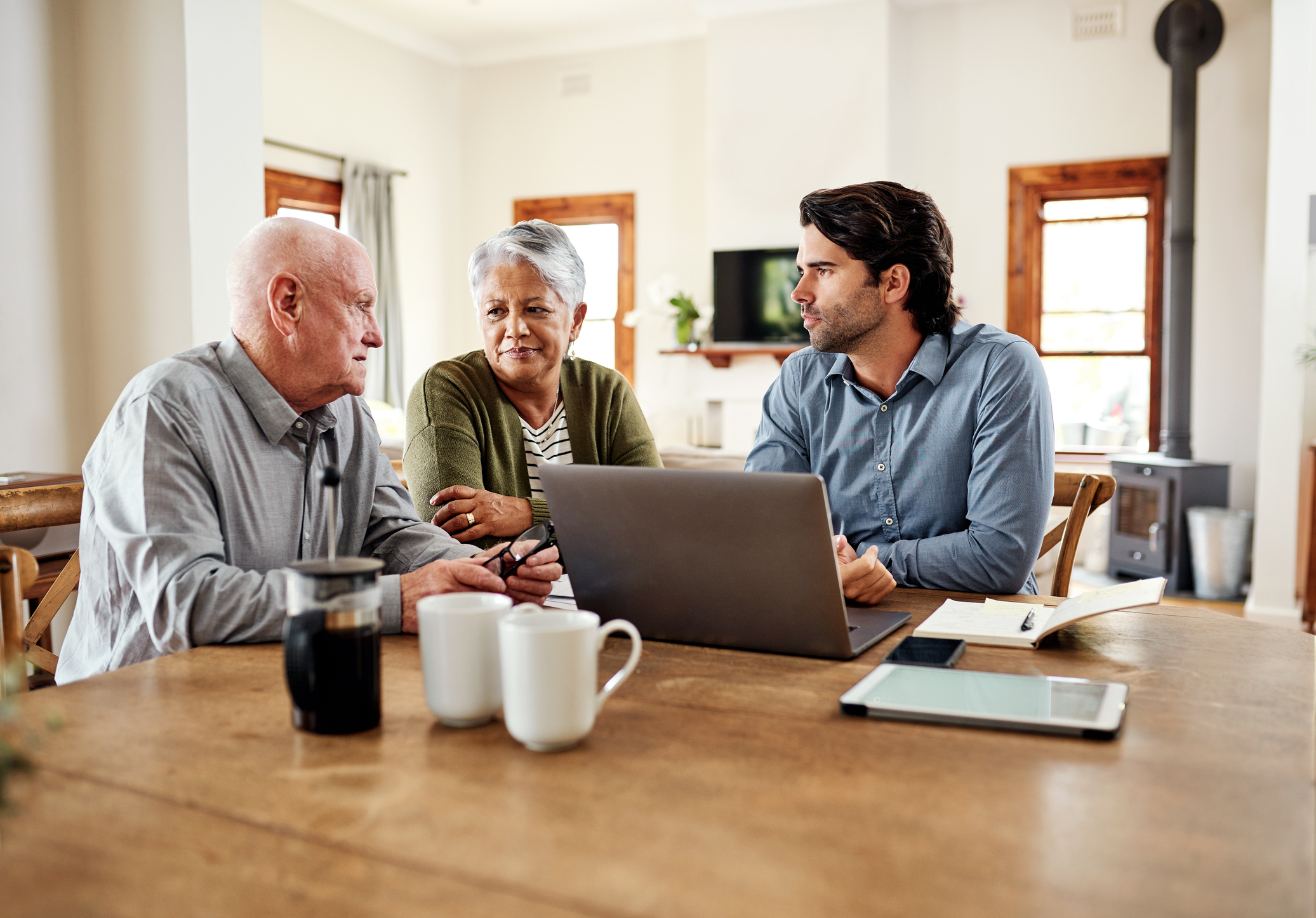 A couple and their financial advisor are sitting at a table discussing their finances.