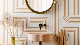 Burnt orange swirl patterned tiles on the wall behind a sink to show the bathroom trend for using pattern