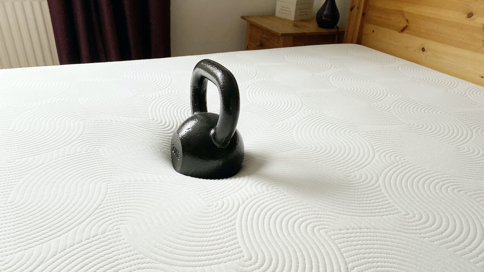 Image shows a 20kg black weight placed in the middle of the Brook + Wilde Lux Mattress during a pressure relief test