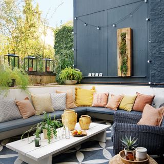 patio area turned into an outdoor living room with monochrome paving and lots of cushions