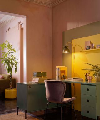 A pink home office with sage green office desk and pink upholstered chair
