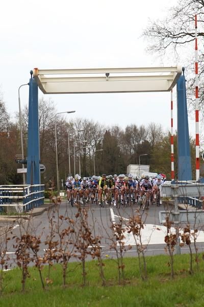 The peloton crosses a canal bridge